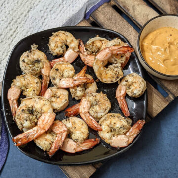 Air fried lemon pepper shrimp on a black plate